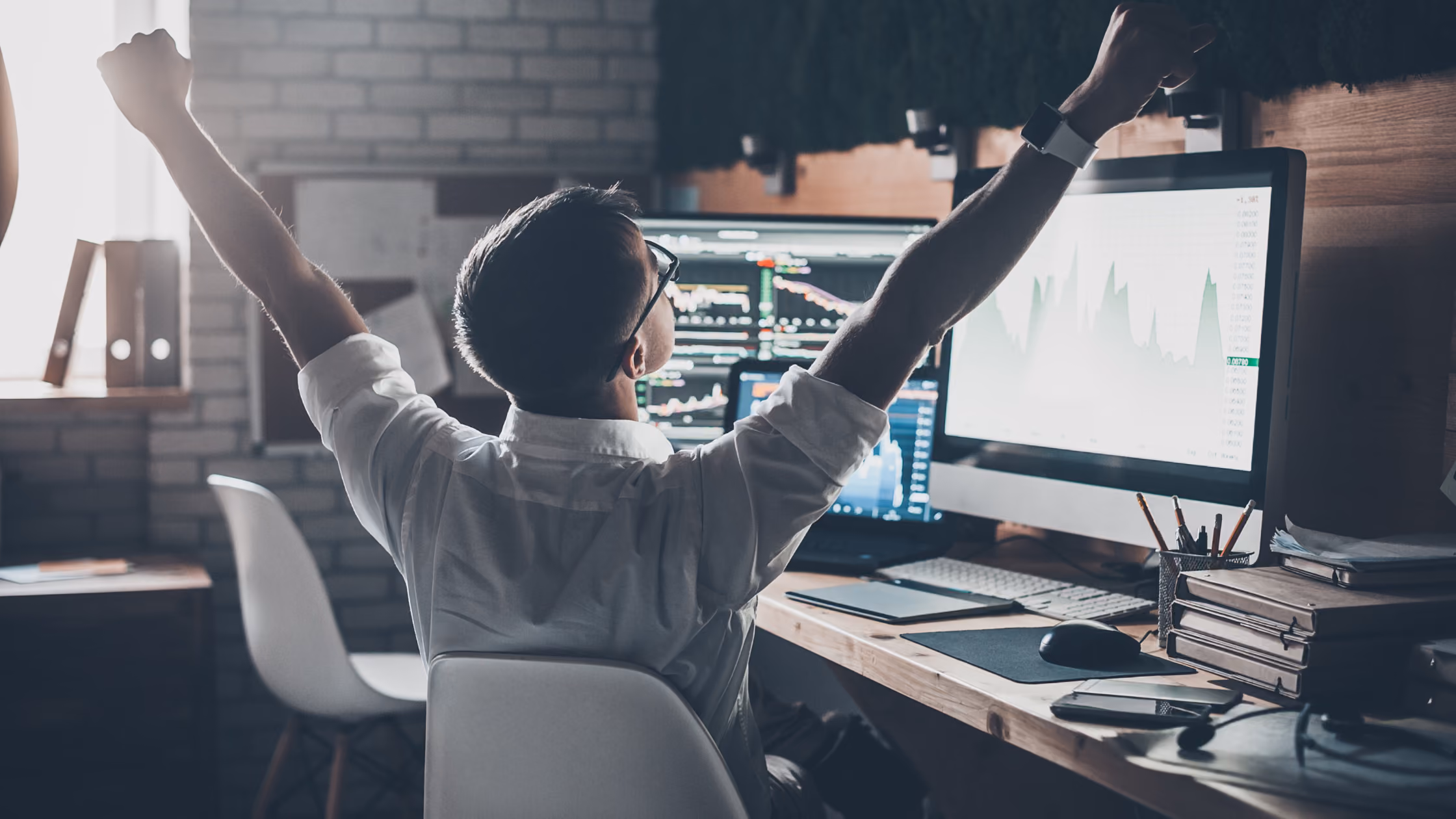 A developer looking at multiple monitors raises his arms in celebration because he isn’t managing MLS data on his own.
